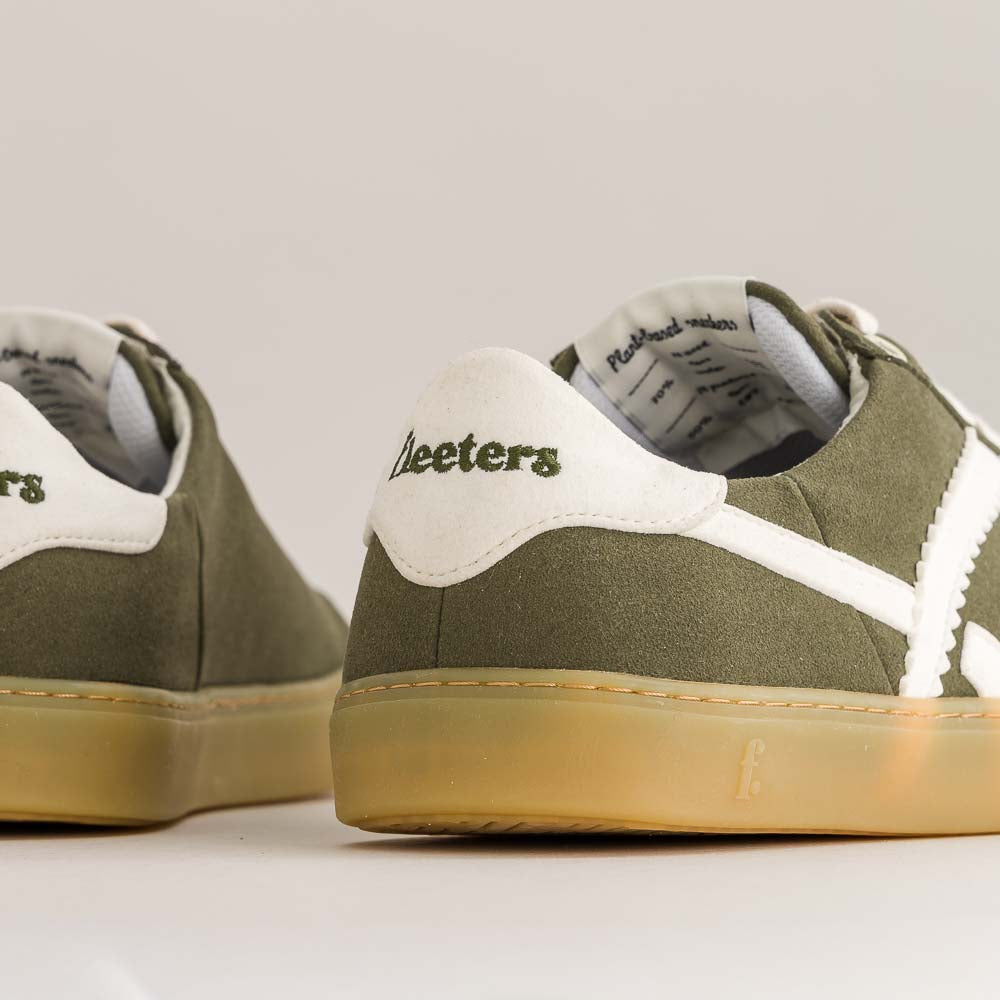Green sneakers with white soles on a light gray background
