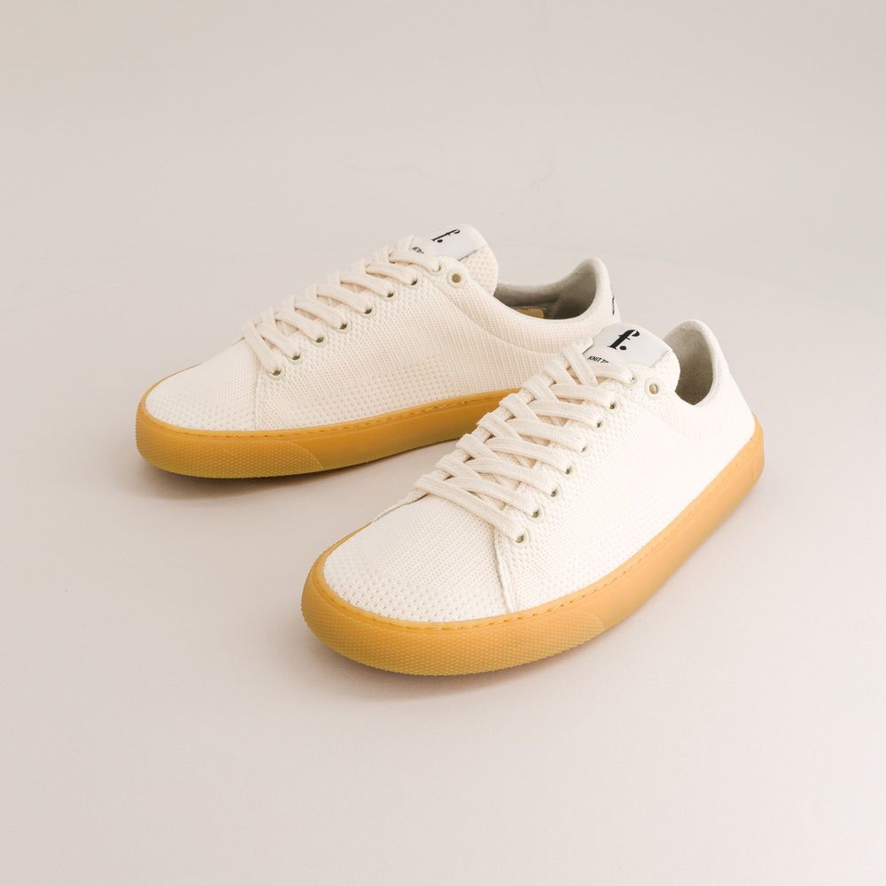 White knit barefoot sneakers with yellow soles on a light gray background