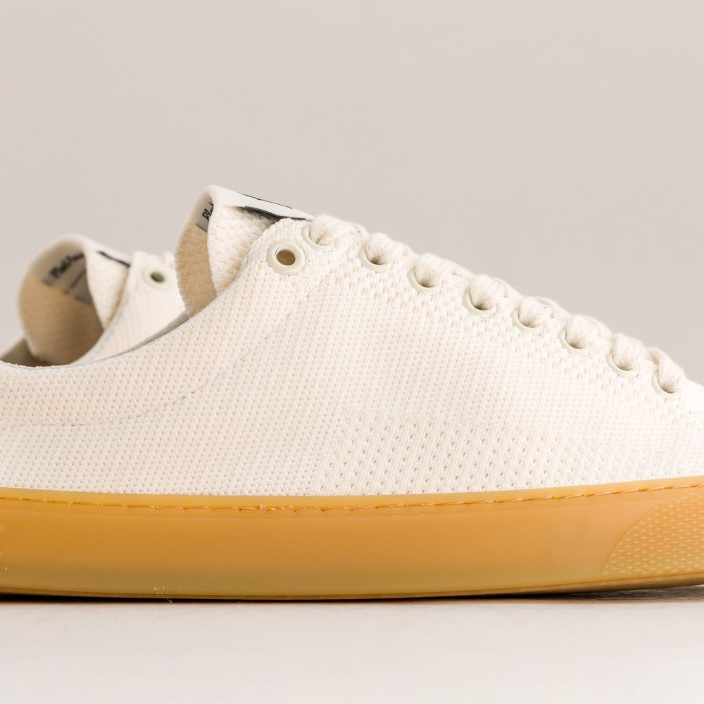 White knit barefoot sneaker with yellow sole on a light gray background