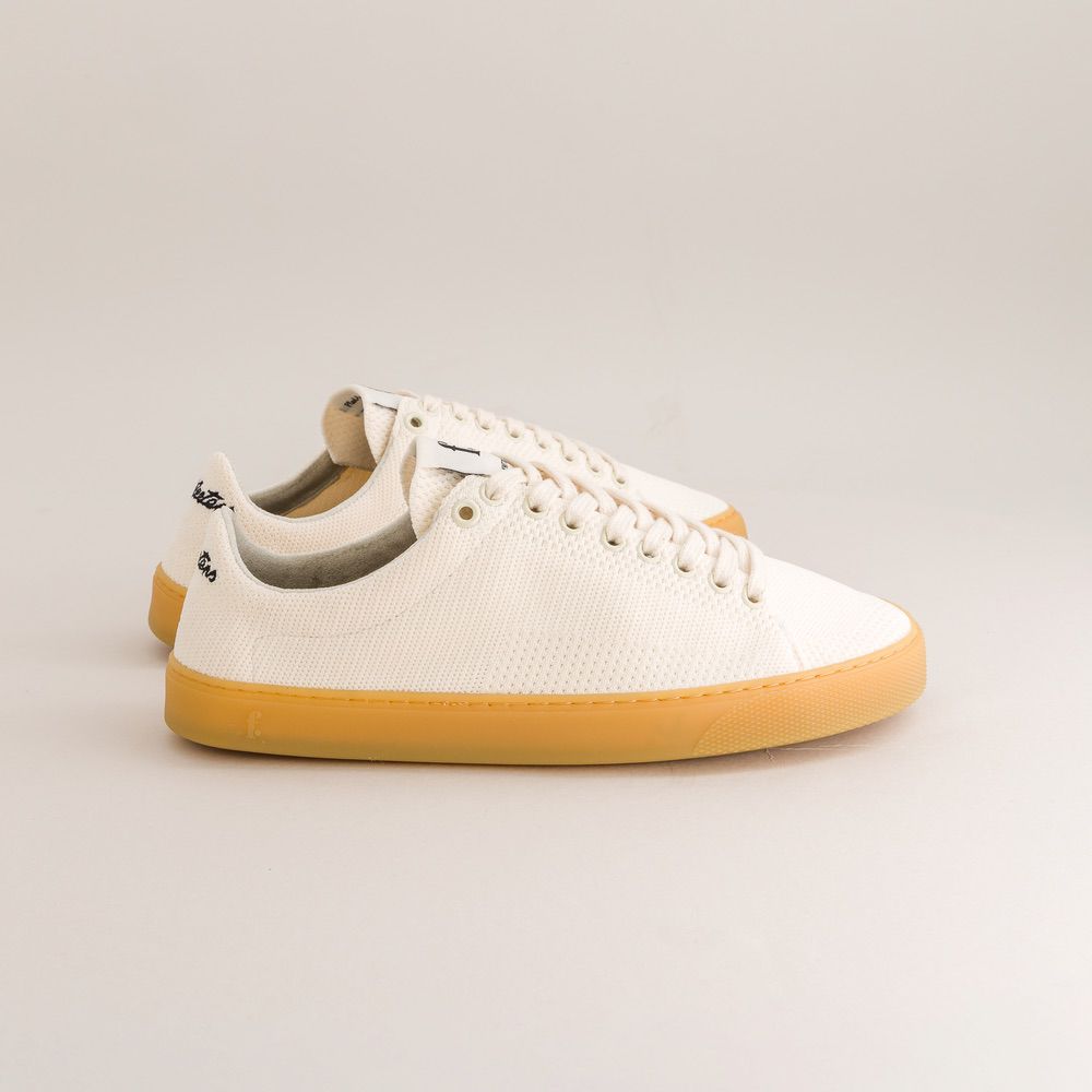 White knit barefoot sneaker with brown sole on a light gray background