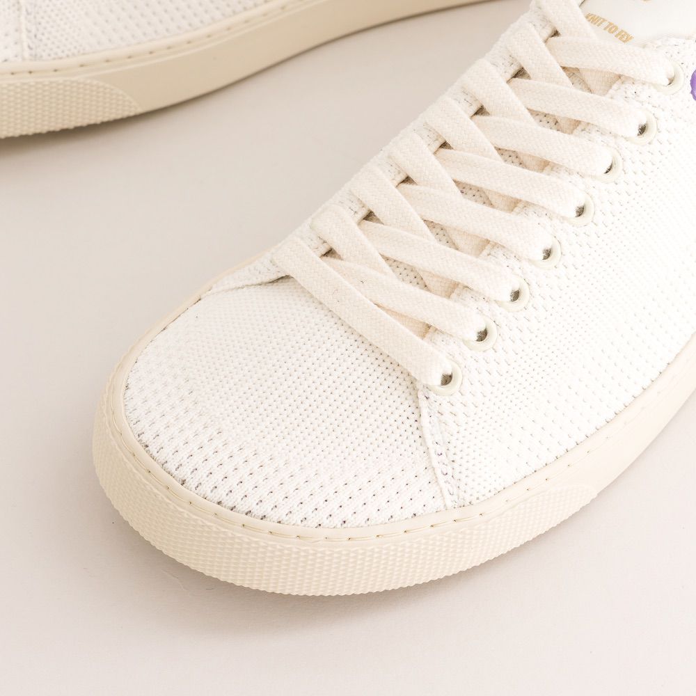 Close-up of a white knit barefoot sneaker with a light background
