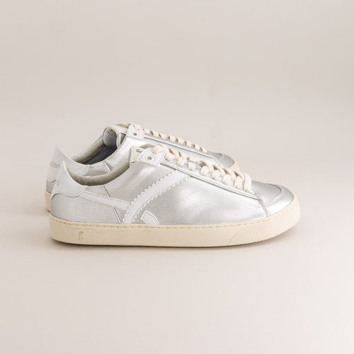 Silver barefoot sneaker with white laces on a beige background