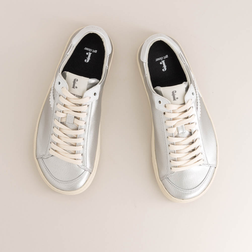 Pair of silver barefoot sneakers on a beige background