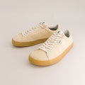 Pair of beige barefoot sneakers with white laces on a light gray background