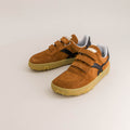 Pair of brown children's barefoot sneakers with velcro straps on a light beige background