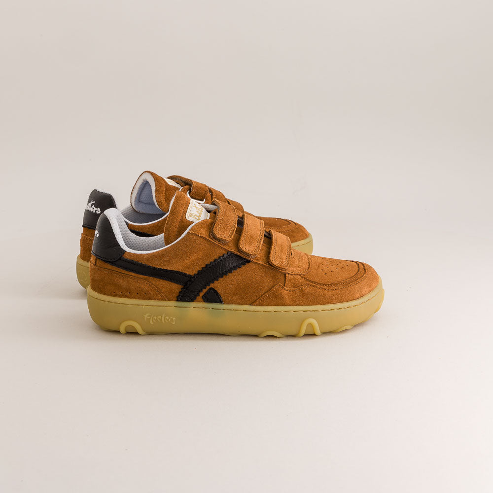 Pair of brown children's barefoot sneakers with velcro straps on a light gray background