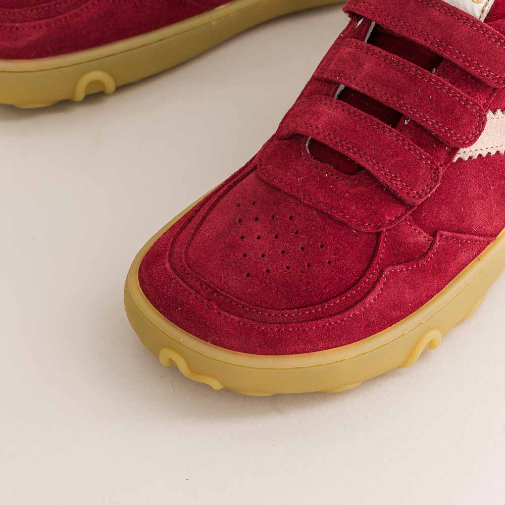 Red children's barefoot shoes with yellow soles on a light background