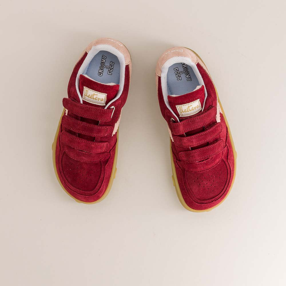 Red children's barefoot sneakers with velcro straps on a beige background