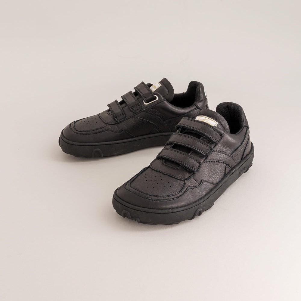Pair of black barefoot sneakers for kids with velcro straps on a light gray background