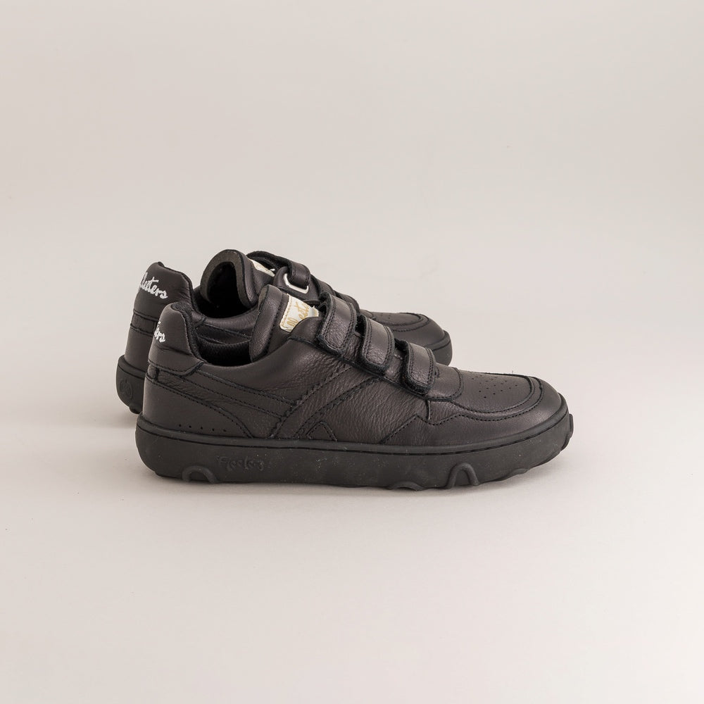 Pair of black kids barefoot sneakers with velcro straps on a light gray background