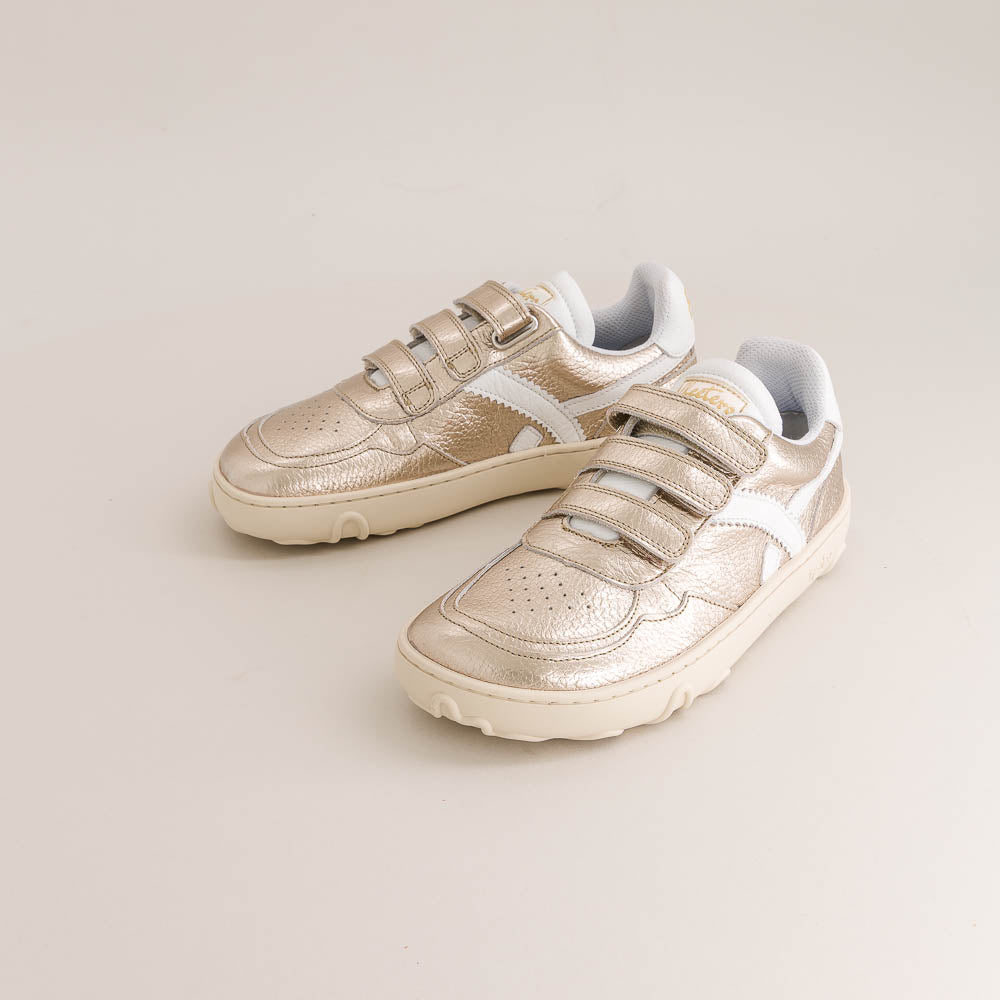 Pair of gold kids barefoot sneakers on a light gray background