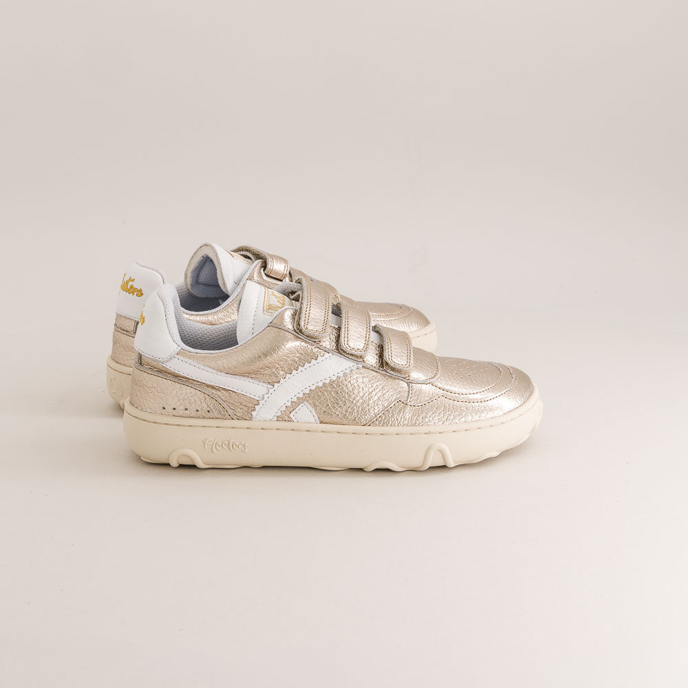 Gold and white kids barefoot sneaker on a light beige background