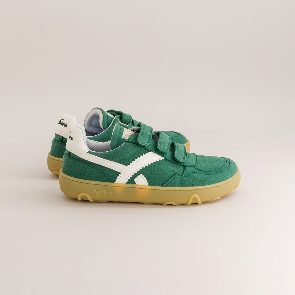 A pair of green toddler barefoot sneakers with white side stripes, double hook-and-loop straps, and gum soles, photographed on a light gray studio background.