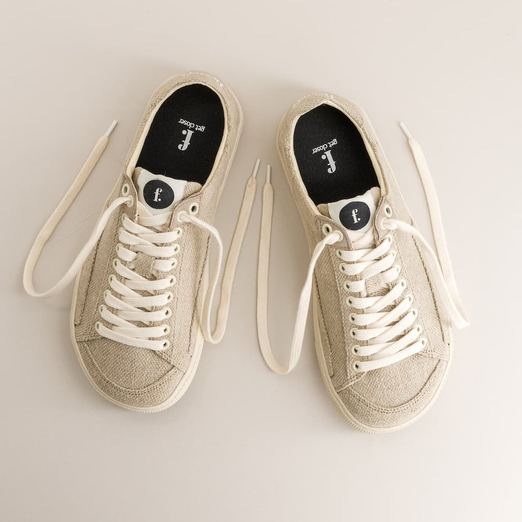 Pair of beige barefoot sneakers in wool with white laces on a light gray background