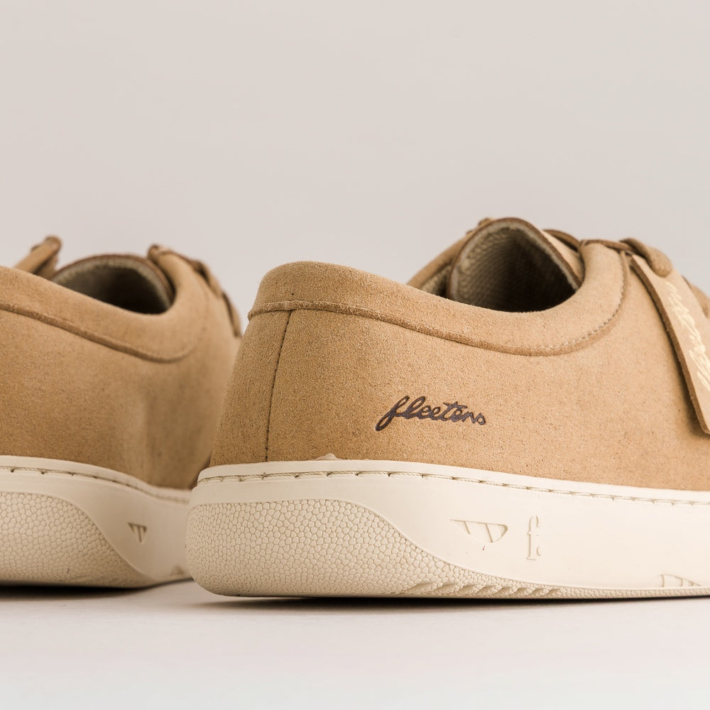 Close-up of tan suede Fleeters sneakers with off-white textured soles, showing the side heel and embroidered 'Fleeters' logo.