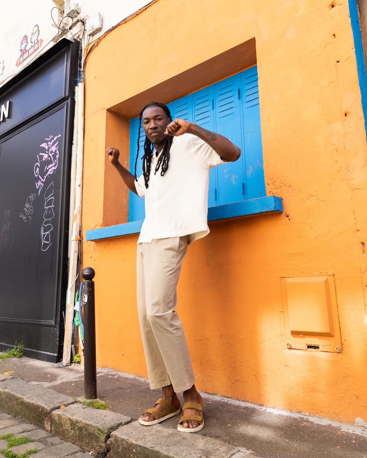 Person standing in front of a colorful building with blue shutters