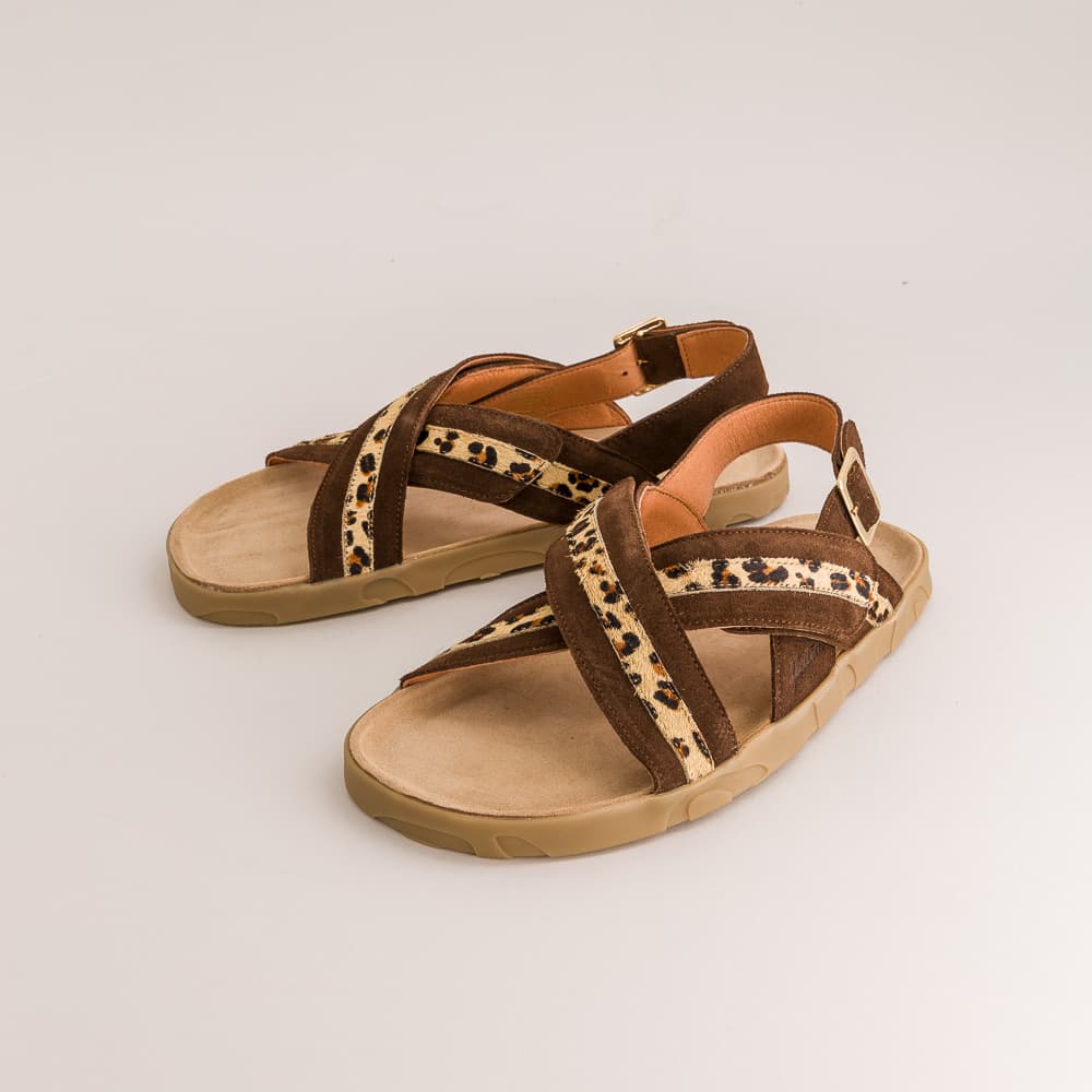 A pair of women's strappy sandals with brown suede-like straps, leopard-print patterned bands, and tan soles, shown on a light gray background.