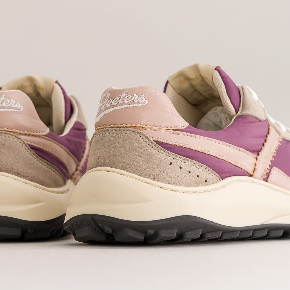 A close-up of a pair of retro-style chunky barefoot sneakers, showing the side and heel details. The shoes feature a combination of dusty purple, light pink, beige suede, and cream midsoles with black outsoles.