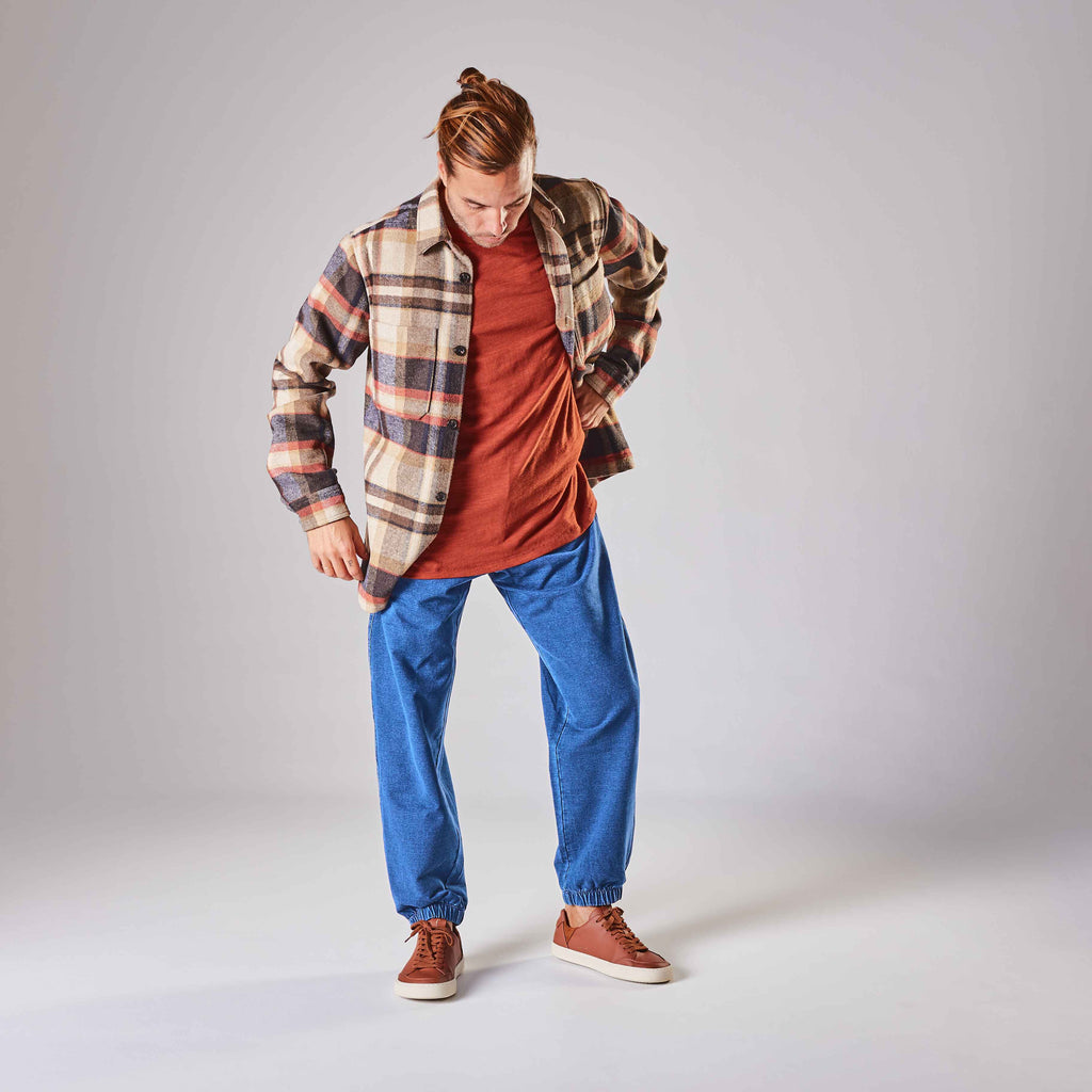 Man standing wearing plaid shirt, blue jeans, and lemon brown barefoot shoes