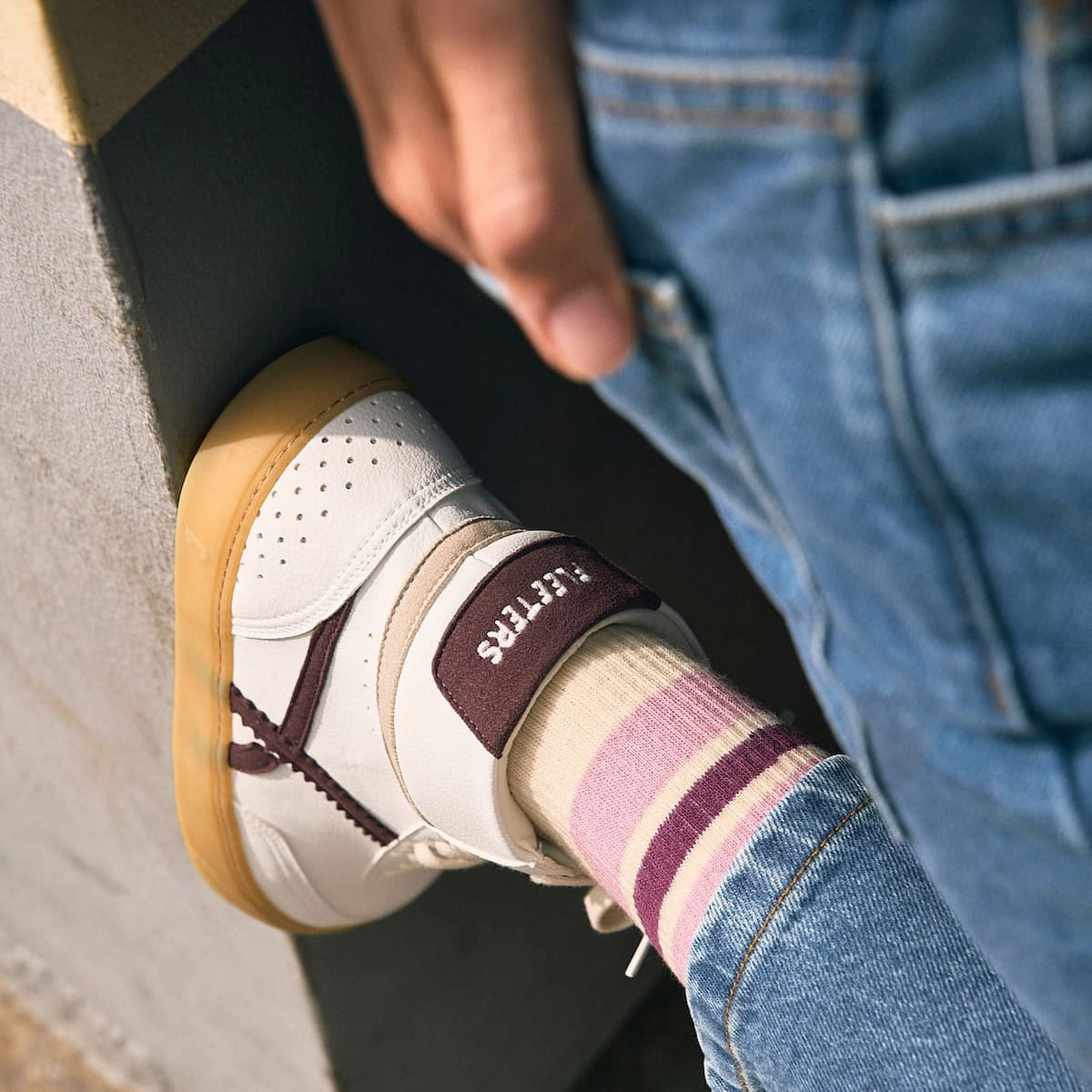 person wearing white barefoot sneaker mid top with yellow sole on a beige