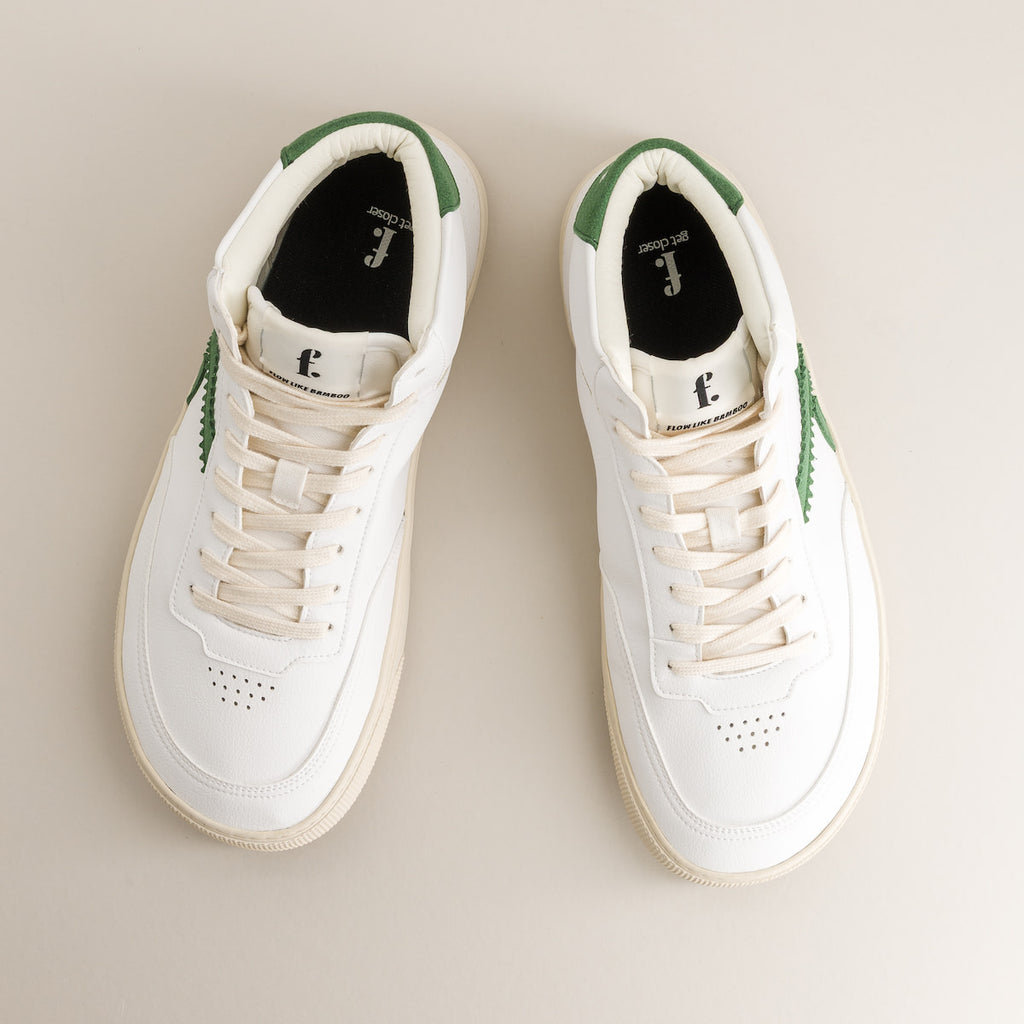 Pair of white barefoot sneakers with green accents on a beige background