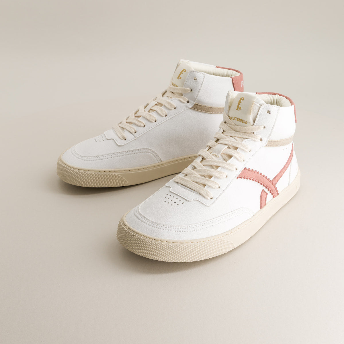 White mid-ankle barefoot sneakers with pink accents on a beige background