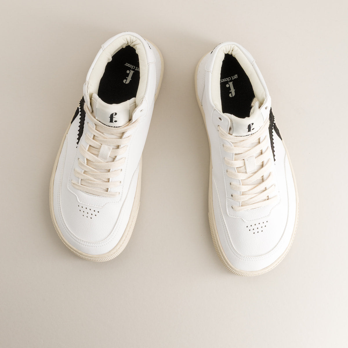 Pair of white barefoot sneakers on a beige background