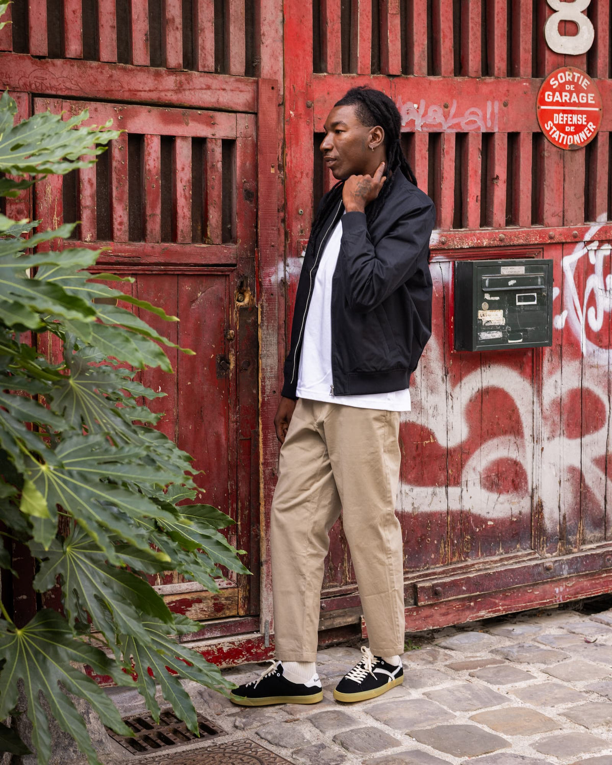 Man wearing black barefoot sneakers in front of a red door