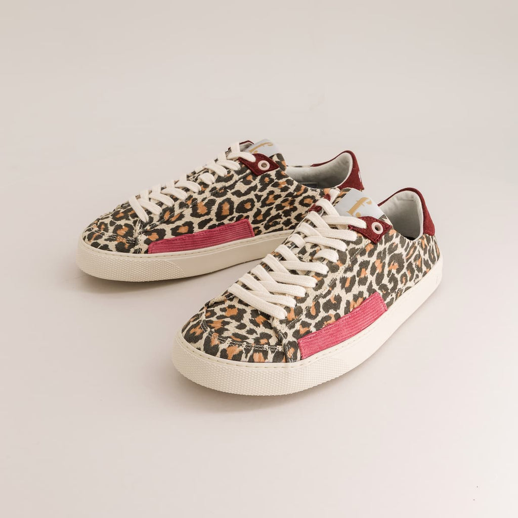 A pair of low-top barefoot canvas sneakers featuring a leopard print pattern, white laces, a pink side stripe, and a burgundy heel tab, displayed on a light gray background.