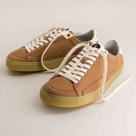 Pair of brown barefoot sneakers with white laces on a light beige background